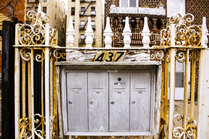 This is an rusty, old painted white gate located at 437 East 116th Street.