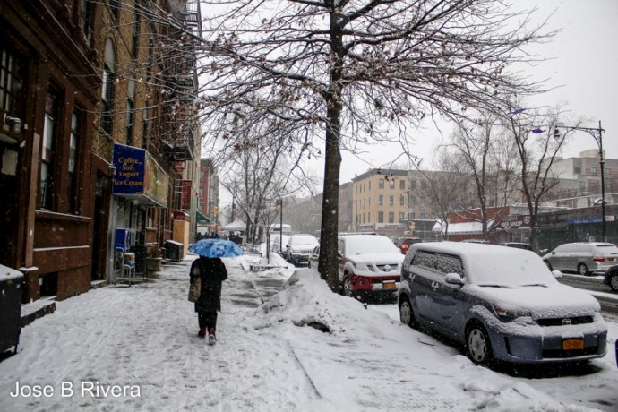 Sole pedestrian walking on a snowy day on East 116th Streets.