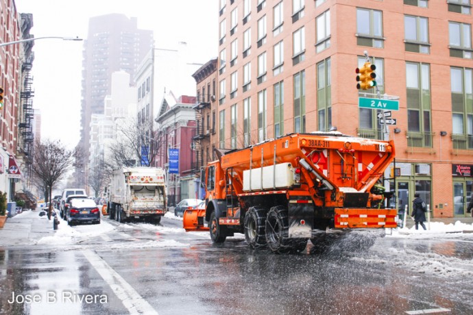 Big orange snow plow salts the road as it plows. This one is on Second Avenue heading toward First Avenue on East 110th Street.