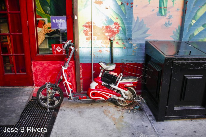 Red bike against a blue wall, downtown near East 5th Street between Second and First Avenues.
