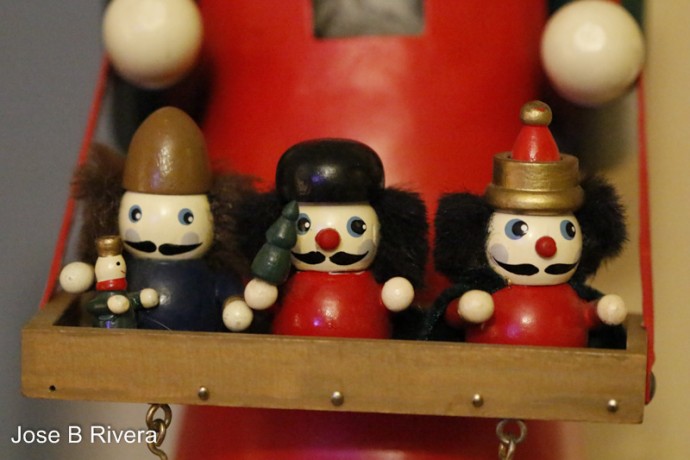 Small wooden toys sit on a larger wooden toy's tray.