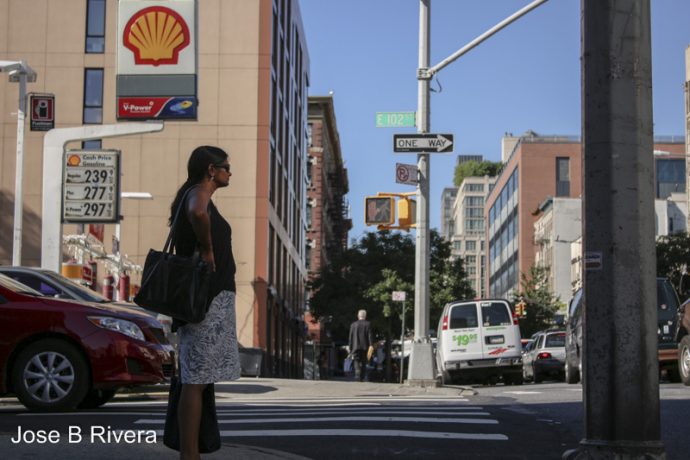 Photo of a lady waiting to cross Lexington Avenue at East 102nd Street, atop the "hill'.