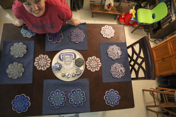 Wife looks up after setting up the colorful Trivets on our dinning room table.