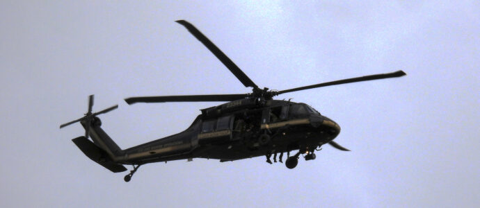 Helicopter flies over head with feet dangling over the edge.